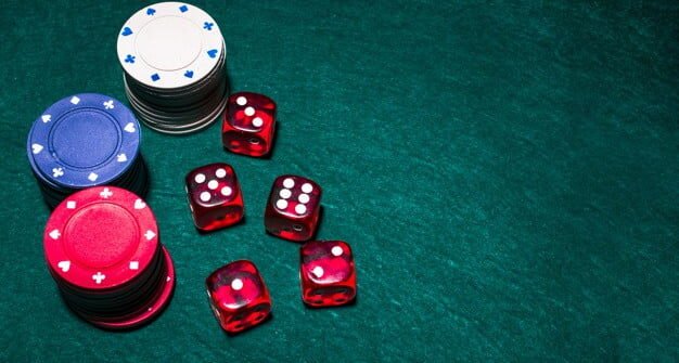 red dices and poker chips on a green table